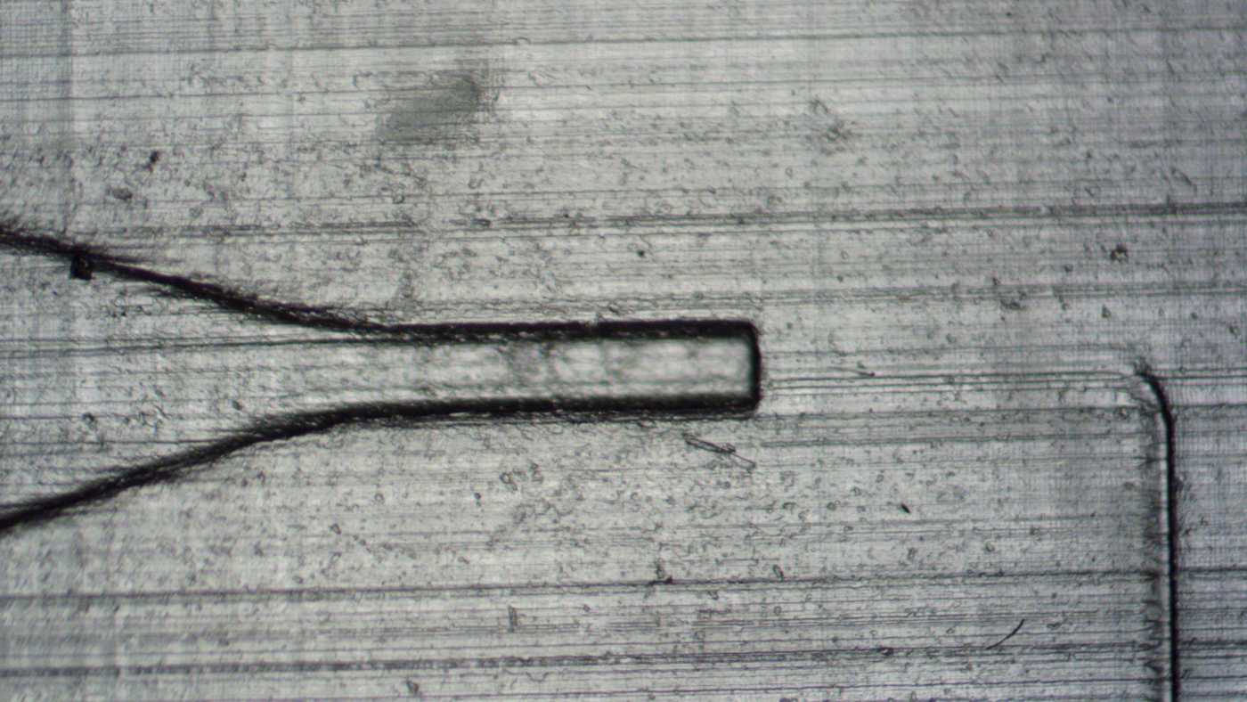 Close-up of a 3D printed capillary valve and sloped microfluidic channel. The surfaces are rough with clearly visible layers.