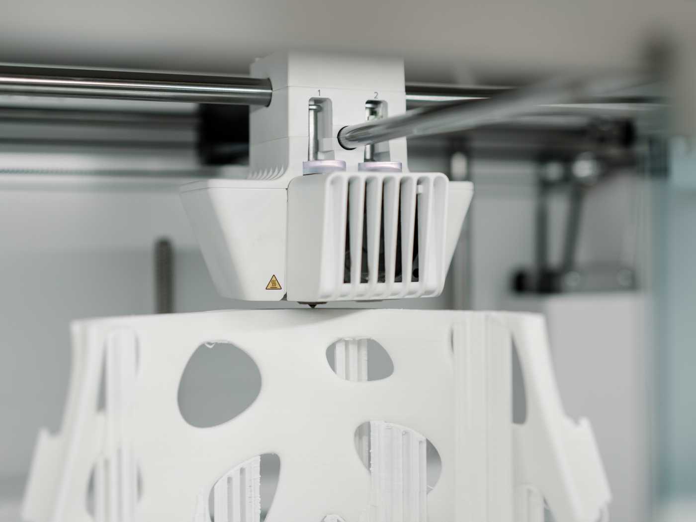 The extruder of an FDM 3D printer that is in the process of printing a model.